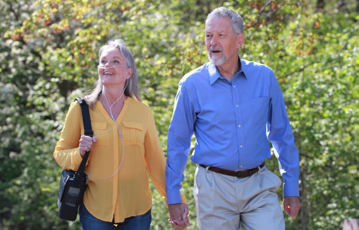 A couple walking outdoors while using supplemental oxygen